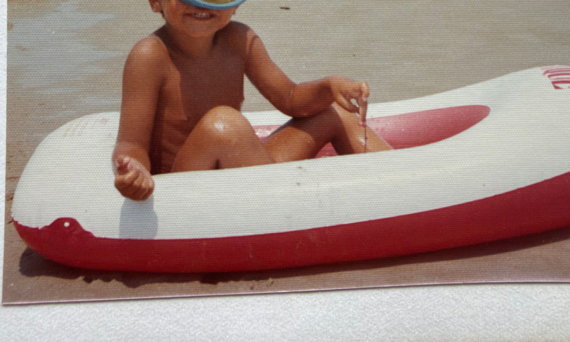 Jongetje met een duikbril op in een opblaasbootje op het strand